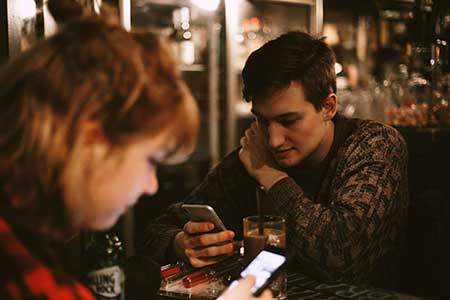 man and woman looking at cellphones